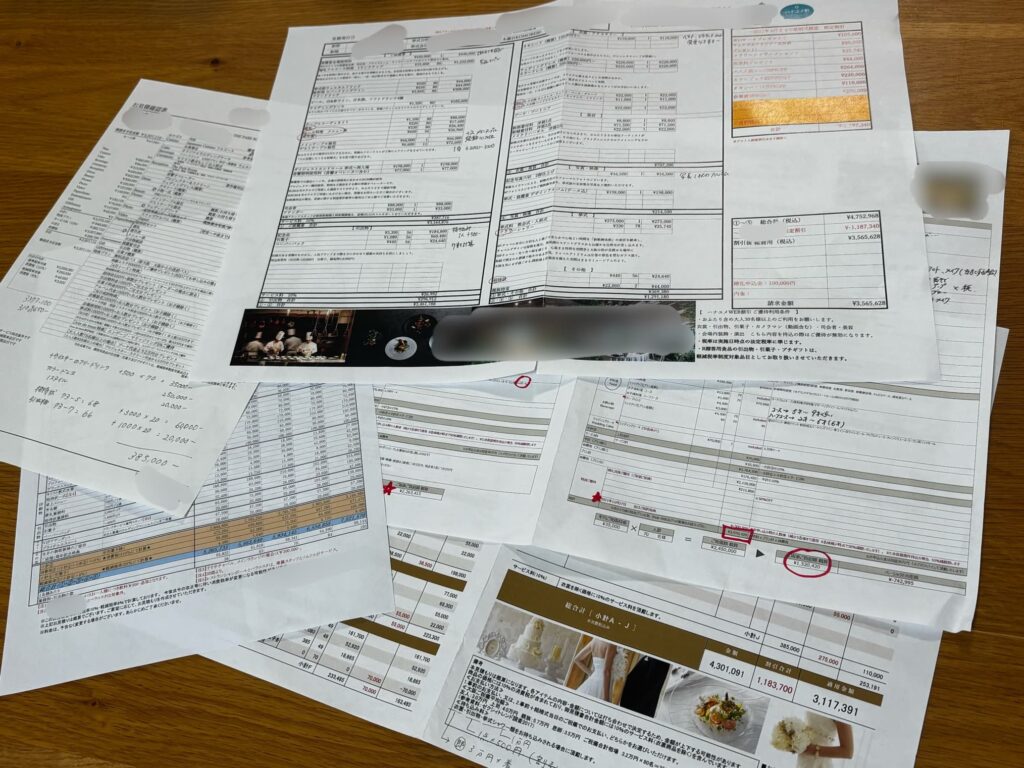実際に見学して集めた複数の結婚式場の見積書を広げ、割引前後の金額を赤ペンで比較した写真。式場名は伏せている