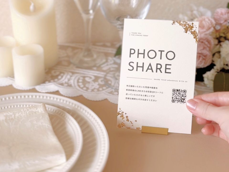 結婚式のゲストテーブルに飾られたフォトシェアカード。QRコードから写真や動画を新郎新婦に送れる案内付き