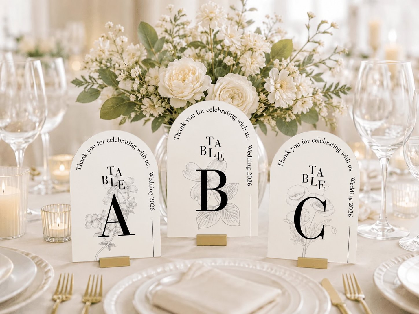 アーチ型の結婚式テーブルナンバー（TABLE A・B・C）を白い花装飾とともに並べたテーブルコーディネート